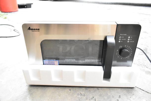 Brand new 2021 Amana RMS10DSA stainless steel commercial microwave with dial controls, in crate, model visible.