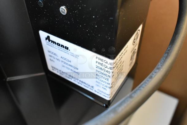 Brand new Amana AOC24 stainless steel commercial microwave. Features touch pad, 208-240 volts, model and safety label visible.