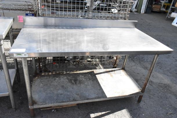 Stainless steel table with backsplash, features a metal undershelf and visible wear. Label shows "Regency NSF" certification.