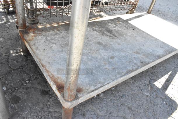 Stainless steel table with a back splash and metal under shelf. Visible rust on legs, indicating wear.
