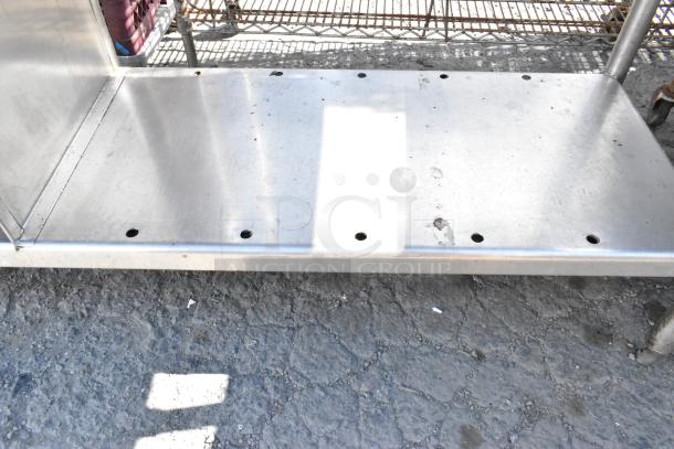 Stainless steel table with metal under shelf, sturdy construction, visible scuffs, suitable for kitchen or industrial use.