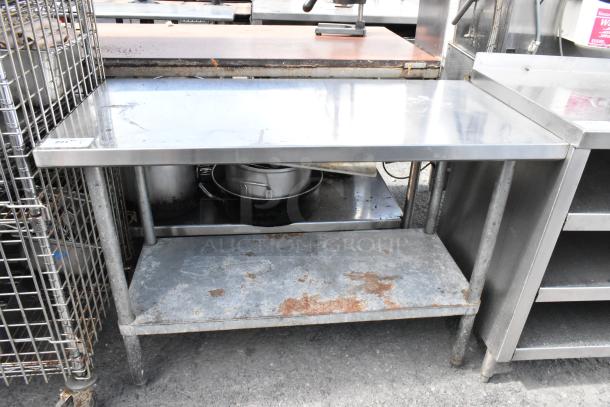 Stainless steel table with metal under shelf, showing signs of wear and rust. Ideal for industrial kitchen use.