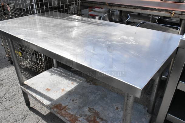Stainless steel table with metal under shelf, showing wear and surface scratches, ideal for commercial use.