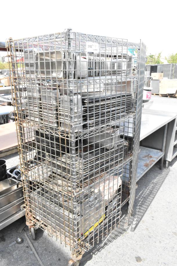 Chrome 5-tier wire shelving unit on casters with liquor cage, food warmer, stainless bins. Buyer must dismantle.