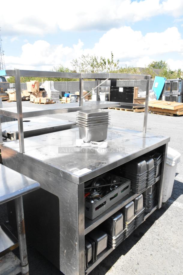 Stainless steel table with over and under shelves, containing stainless steel drop-in bins, in good condition.