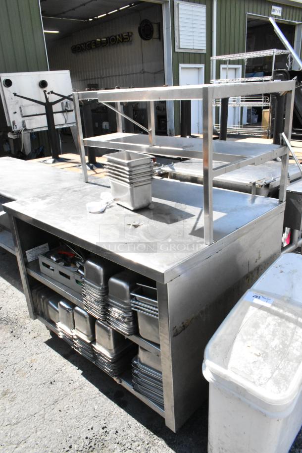 Stainless steel table with over shelf and under shelf, includes stainless steel drop-in bins. Visible signs of use.