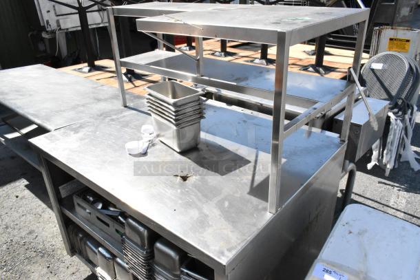 Stainless steel table with over and under shelf, includes stainless steel drop-in bins, minor wear visible.