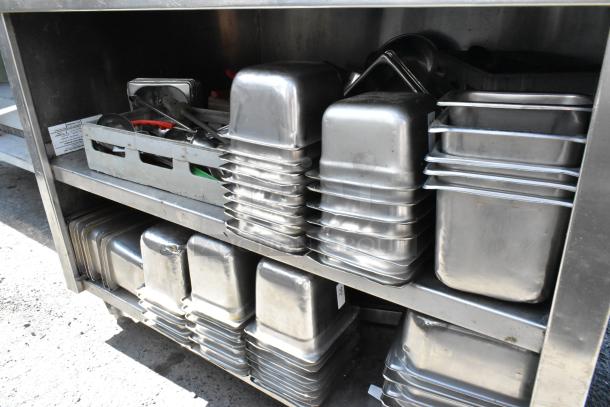 Stainless steel table with over shelf, under shelf, and contents including stacked stainless steel drop-in bins in good condition.