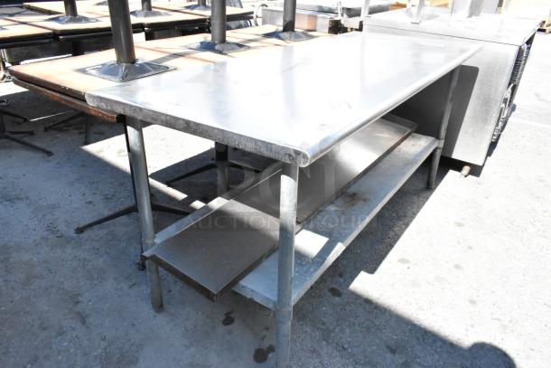 Stainless steel table with sturdy metal under shelf, showing light wear. Ideal for kitchen or industrial use.