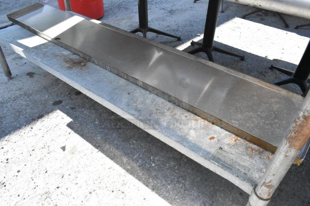 Stainless steel table with metal under shelf, used condition, visible wear and rust. Manufacturer label on lower shelf.