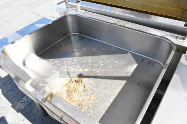 Stainless steel commercial manual tilt braising pan, large capacity, used condition, minor food residue visible.