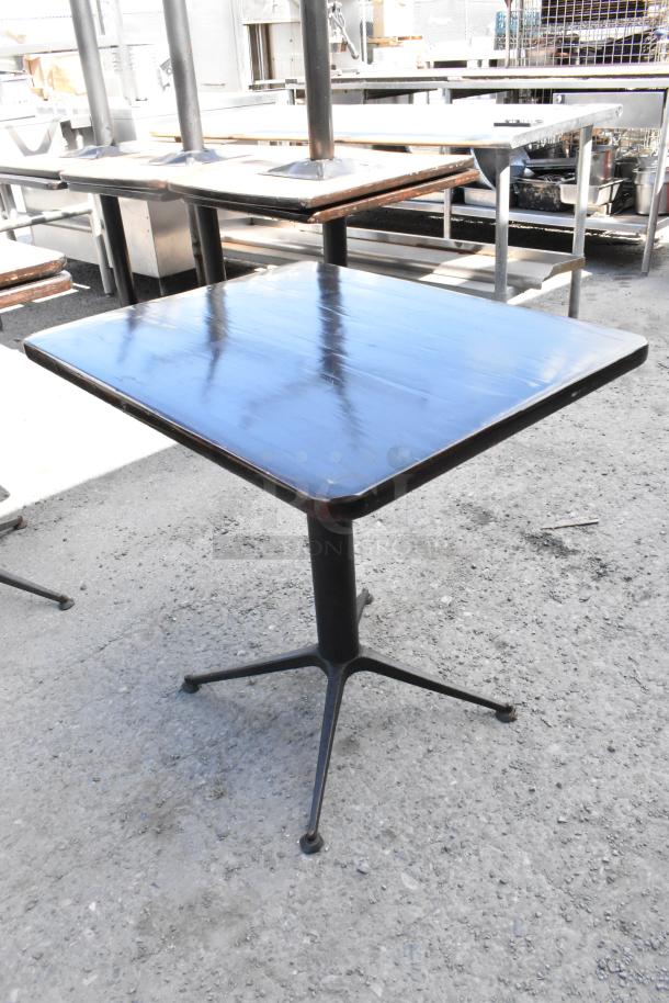 9 dining height tables with square wooden tops and metal bases, used condition, suitable for restaurant or café.