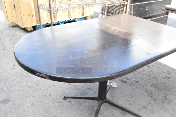 Vintage black dining table with rounded edges, metal pedestal base. Surface shows wear. Part of a set of three tables.