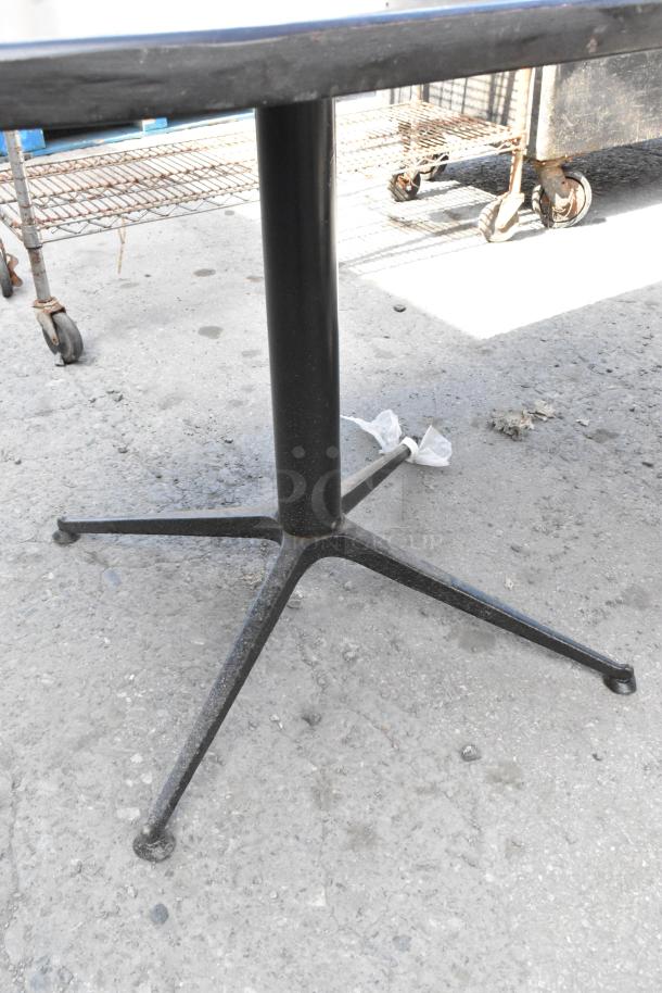 Three dining height tables with sturdy black metal bases, shown outdoors on concrete. Some wear visible on table edges.