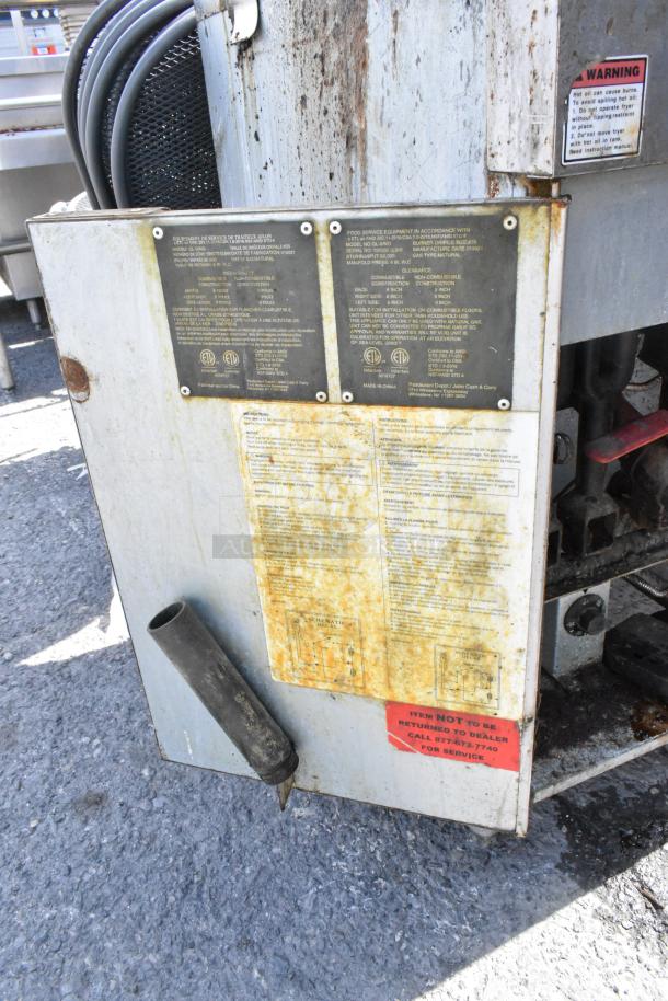 Qualite QL-9/NG fryer with metal baskets, splash guard, and warning label. Visible wear and instructional markings.