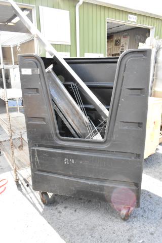 Black poly truck on commercial casters with contents, showing wear. Includes assorted metal items inside.
