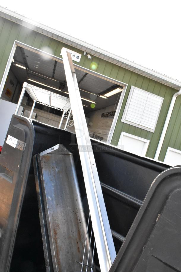 Black poly truck on commercial casters, filled with metal and aluminum contents, visible labels and markings.