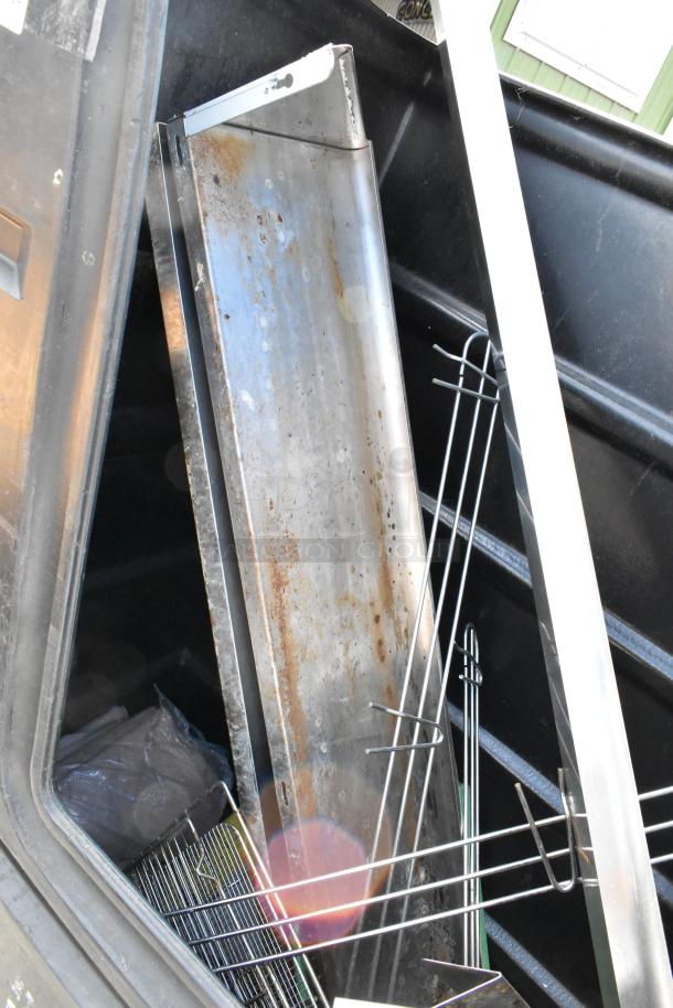 Black poly truck on commercial casters containing assorted metal items, showing signs of rust and wear, used condition.