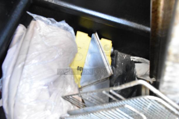 Black poly truck on commercial casters, containing assorted materials and items, including metal sheets and protective wraps.