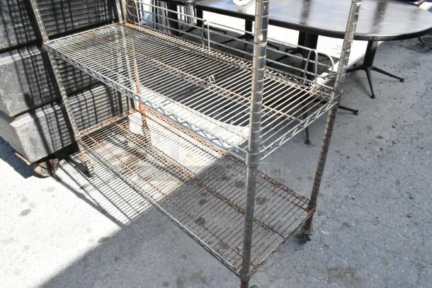 Chrome finish 5 tier wire shelving unit on commercial casters, shows wear and rust. Buyer must dismantle, consider freight.