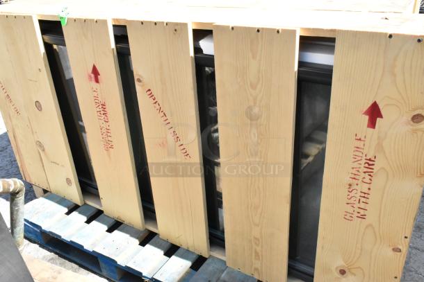 Brand new doors crated for auction, labeled "Glass Handle With Care," wooden crate shows shipping directions.
