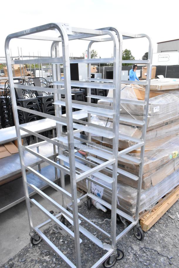 Two metal commercial pan transport racks on sturdy casters, ideal for industrial use, in good condition.