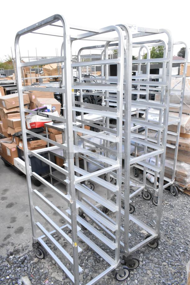 Two metal commercial pan transport racks on casters; one rack missing a caster. Auction includes both racks.