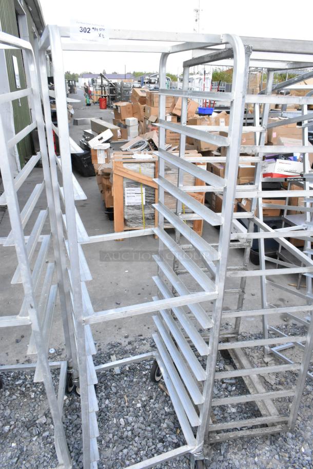 Two metal commercial pan transport racks on sturdy casters, ideal for kitchen use. Includes multiple shelves, signs of light wear.