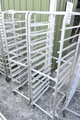 Two metal commercial pan transport racks with multiple shelves, on sturdy casters for easy mobility.
