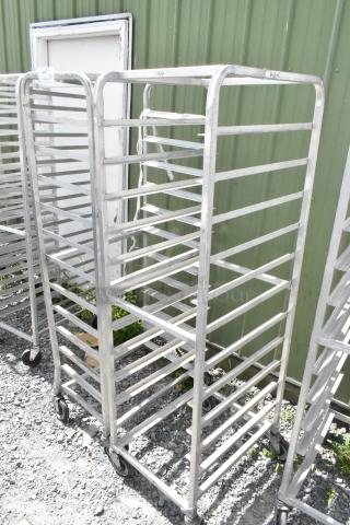 Two metal commercial pan transport racks with multiple shelves, commercial casters, and visible wear. Ideal for kitchens.