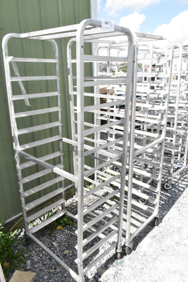 2 metal commercial pan transport racks on casters, used condition. Multiple shelves for holding pans, ideal for kitchen use.