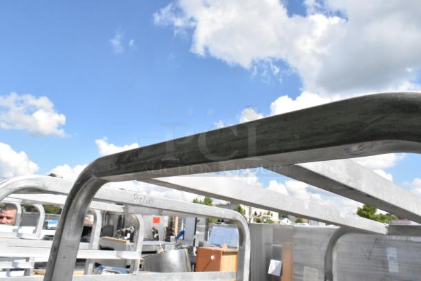 2 metal commercial pan transport racks on casters, outdoor setting, marked "Bakery," showing durable construction.