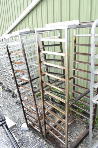 2 metal commercial pan transport racks on casters with rack oven guide, fair condition, outdoor setting.