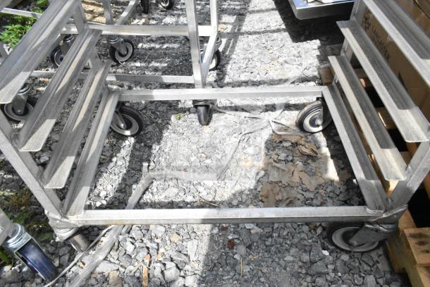 2 metal commercial pan transport racks on sturdy casters, showing wear, designed for heavy-duty use in professional kitchens.