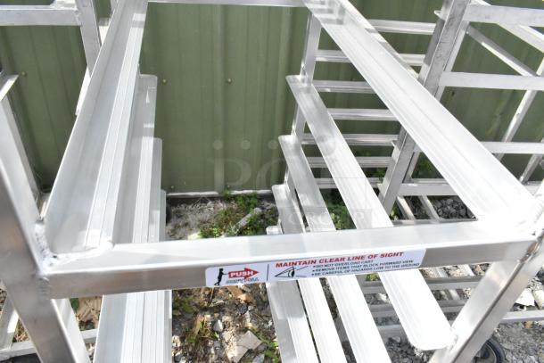 Two metal commercial pan transport racks on commercial casters, featuring sturdy construction and safety instructions label.