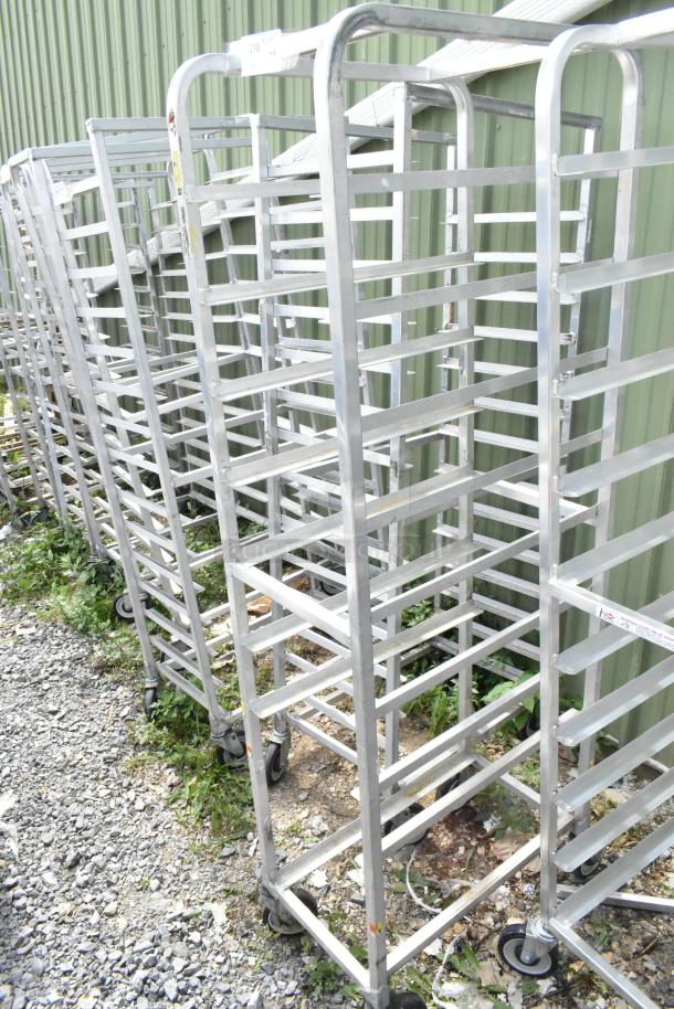 Two metal commercial pan transport racks on commercial casters, sturdy design, outdoor setting, lightly worn condition.
