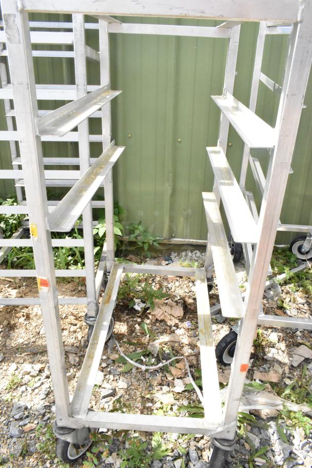 Metal commercial pan transport rack, sturdy frame, on heavy-duty casters, some surface wear, ideal for kitchen use.