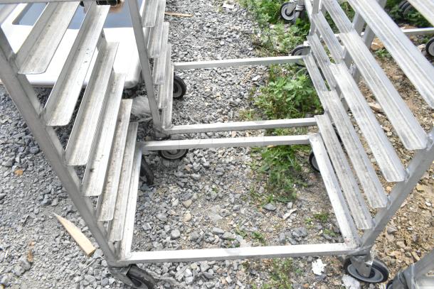 Two metal commercial pan transport racks on casters, suitable for heavy-duty use. Wear visible, ideal for kitchen or catering needs.