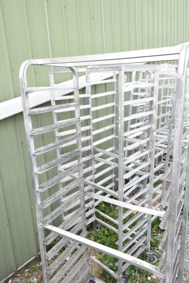 Two metal commercial pan transport racks with multiple horizontal slots, on sturdy commercial casters, showing some wear.