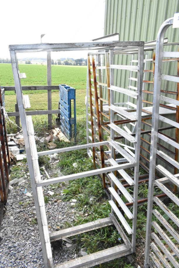2 metal commercial pan transport racks on casters, with rack oven guides, exterior condition visible, outdoors.