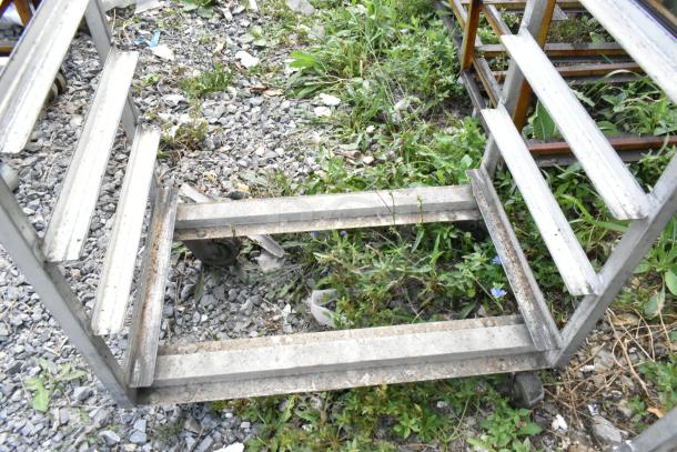 2 metal commercial pan transport racks with casters; includes oven guide; outdoor condition; some rust visible.