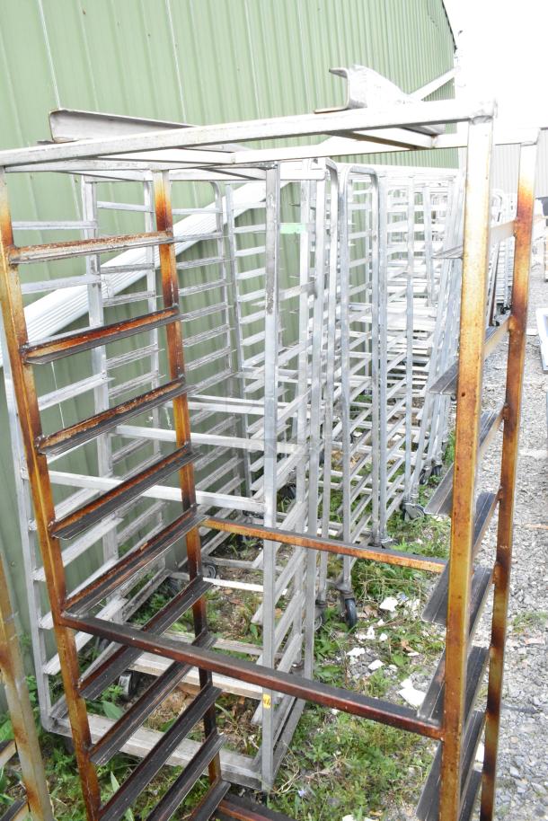2 metal commercial pan transport racks with casters and rack oven guide, rust present, outdoor setting.
