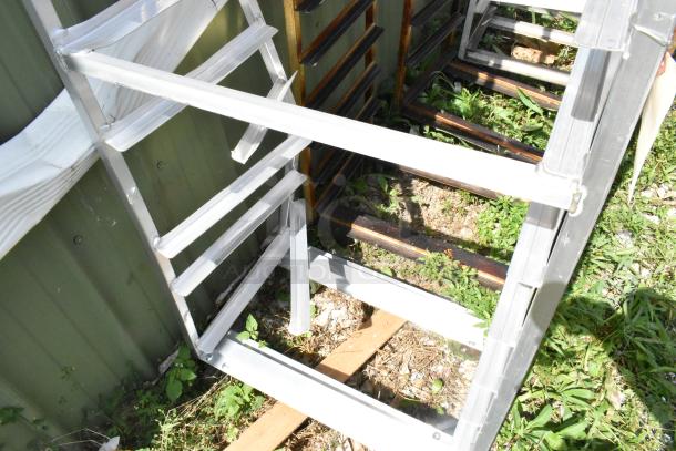 2 metal commercial pan transport racks on casters with oven guide, outdoors, good condition, auction item.