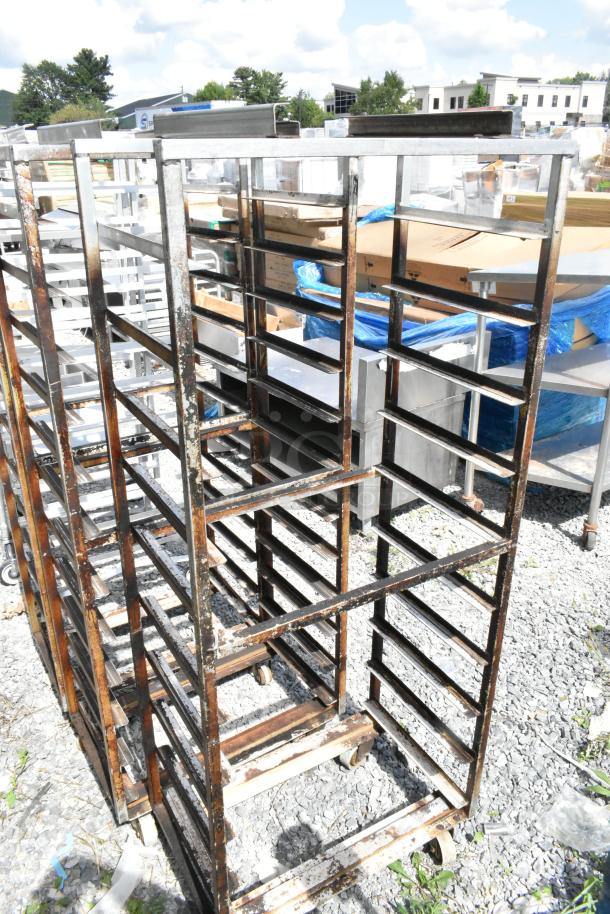 3 Metal commercial pan transport racks on casters with oven guide, showing signs of wear, suitable for industrial use.