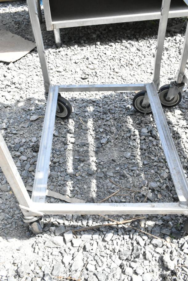 2 metal commercial pan transport racks on commercial casters, sturdy build for kitchen use, condition shows outdoor storage wear.