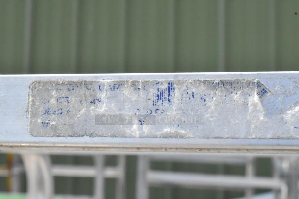 2 metal commercial pan transport racks on casters, showing wear, with a partially faded label indicating previous use.