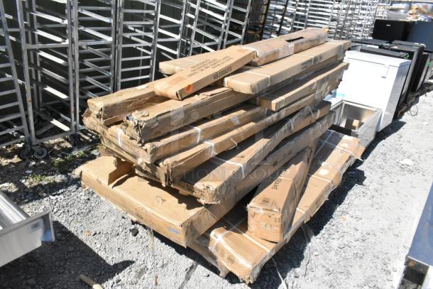 Stack of cardboard boxes containing 20 new scratch and dent items, including over shelf, wire shelves, patio umbrella frames.