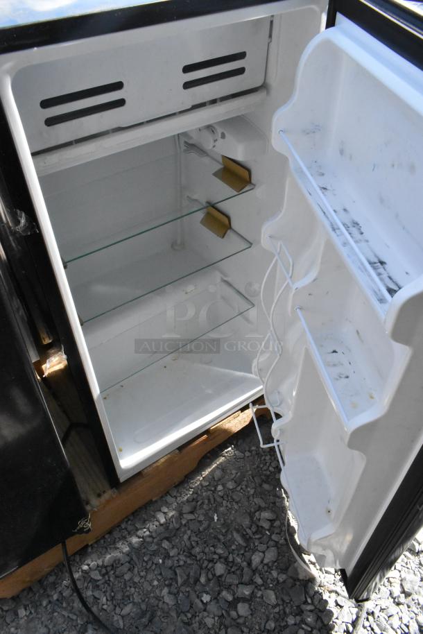 Open black mini cooler with glass shelves and door storage, minor wear. Part of 4-unit auction including Frigidaire, Criterion, Galanz, Midea.