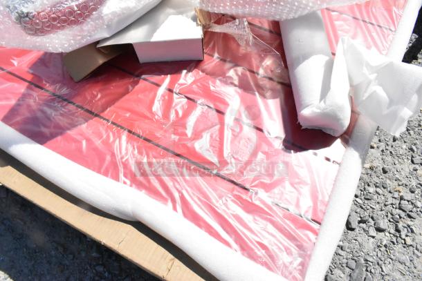 Brand new 427CAU3232RD Lancaster 32" red powder-coated aluminum outdoor table with umbrella hole, wrapped in protective packaging.