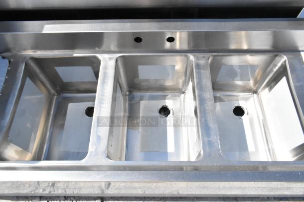 Brand new Regency 600B31014213 stainless steel 3-bay back bar sink with dual drain boards, slight scratches and dents visible.